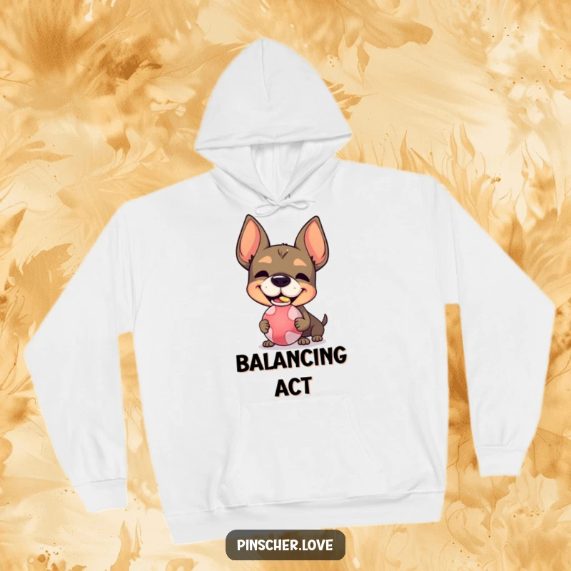 Funny Pinscher character hoodie, with a silly grin, balancing a ball on its nose, offering warmth and playful vibes.