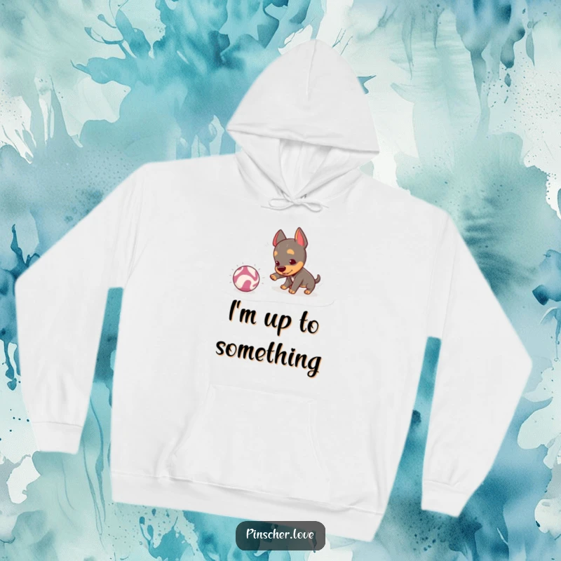 Funny Pinscher Hoodie: A mischievous pinscher playfully nudges a crinkly ball, embodying playful energy and the joy of interactive fun.