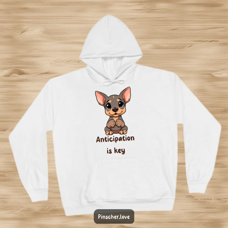 Funny dog hoodie with a Pinscher sitting upright, paws clasped, and a goofy, expectant expression.
