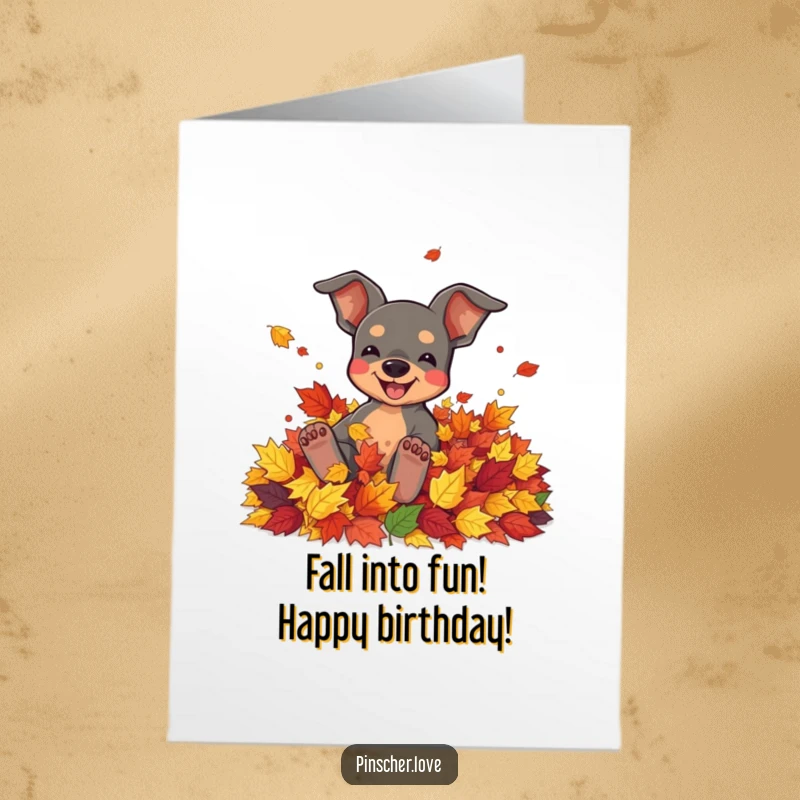Funny Free Printable Birthday Card of a pinscher joyfully rolling in colorful autumn leaves, celebrating with seasonal delight.