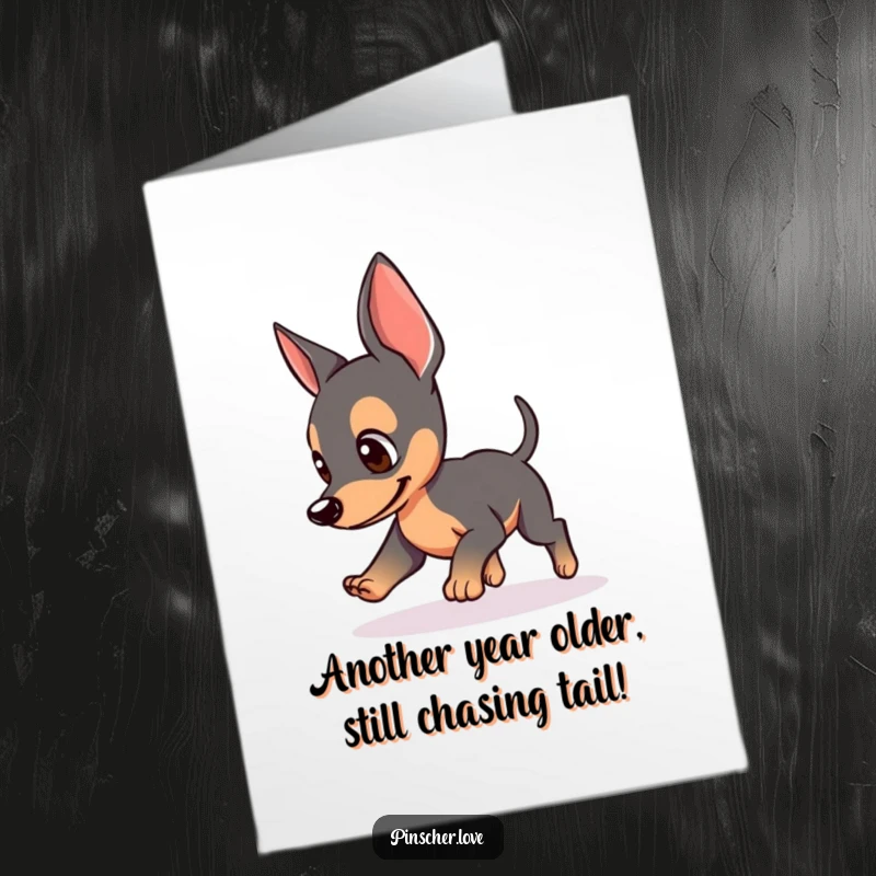 Funny Free Printable Birthday Card featuring a pinscher with perked ears playfully chasing its own tail, full of birthday excitement.