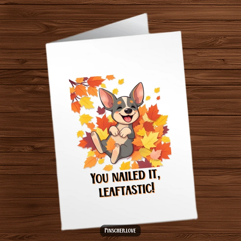 Free printable congratulations card featuring a joyful pinscher dog exuberantly rolling in a colorful heap of autumn leaves.