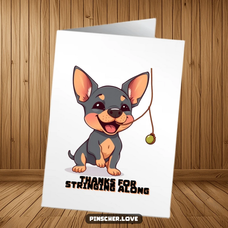 Funny Free Printable Thank You Card: A Pinscher joyfully batting at a dangling, wobbly string, expressing thanks playfully.