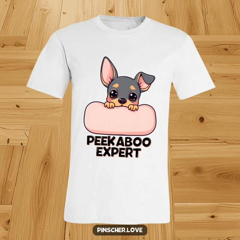 Funny Pinscher t-shirt featuring a cute Pinscher dog peeking from behind a comfy cushion, full of curiosity and playful hope.
