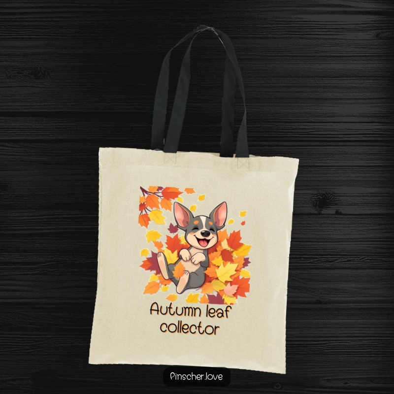 Funny Pinscher tote bag depicting a Pinscher dog having the time of its life rolling in a colorful autumn leaf pile.
