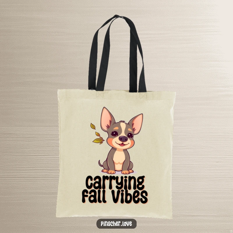 Funny Pinscher tote bag showcasing a delightful Pinscher dog in the act of blowing a tiny, colorful autumn leaf with glee.