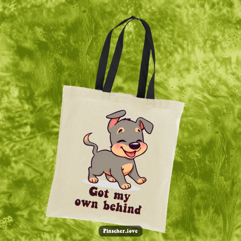 Funny pinscher tote bag featuring a giggling dog humorously chasing its wagging tail, ideal for carrying daily items with glee.